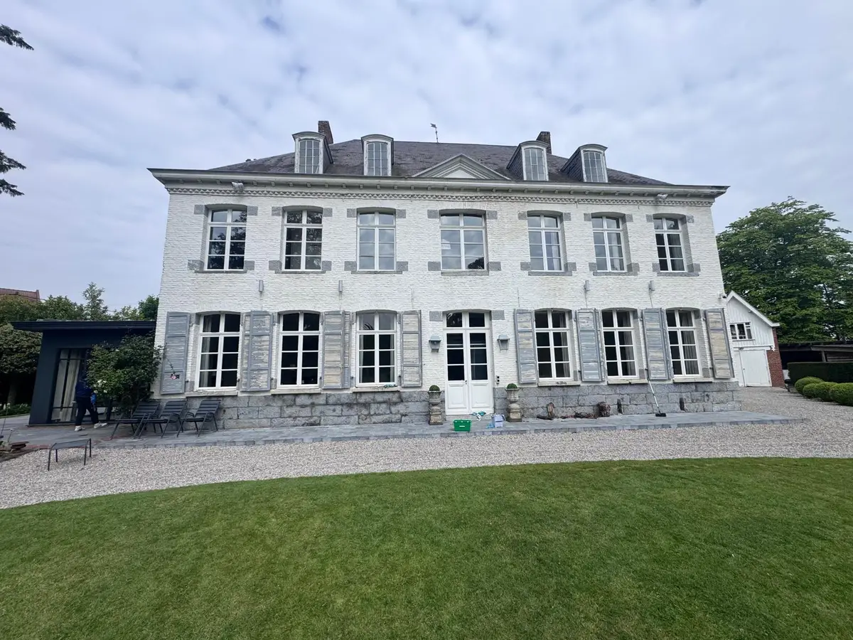 Façade d'une grande maison ancienne aux nombreuses fenêtres à petits carreaux