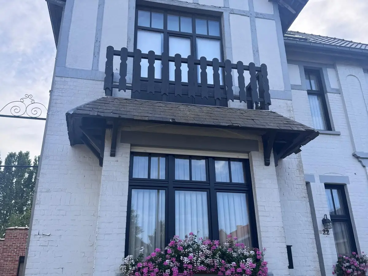 Étage d'une maison blanche avec balcon en bois et grandes fenêtres propres