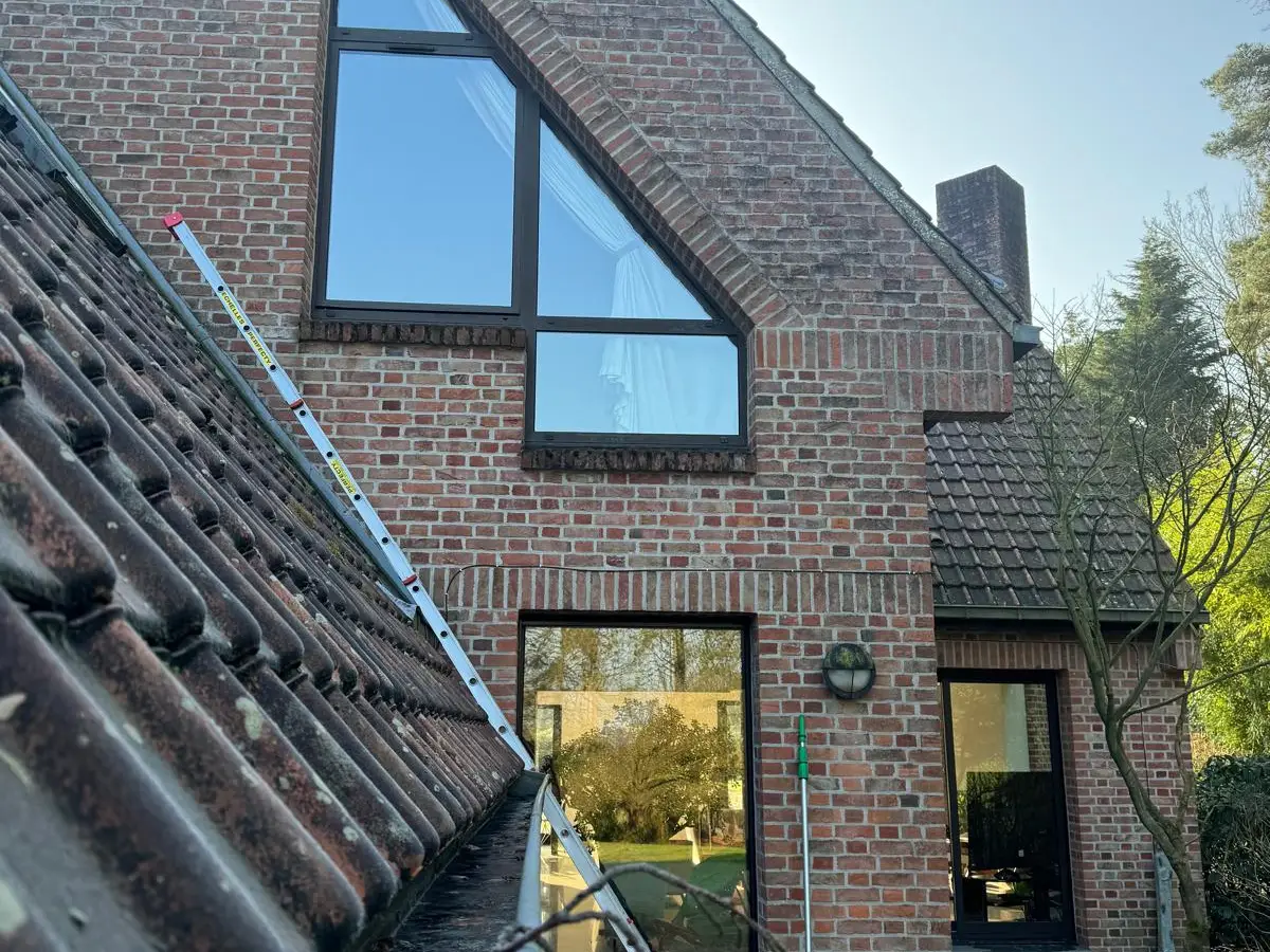 Baie vitrée triangulaire d'une maison en briques avec échelle et seau