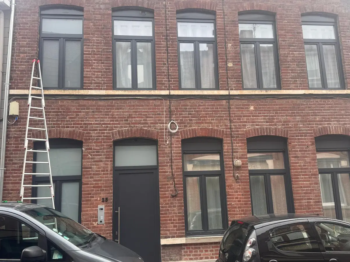 Échelle appuyée contre une façade en briques aux fenêtres sombres