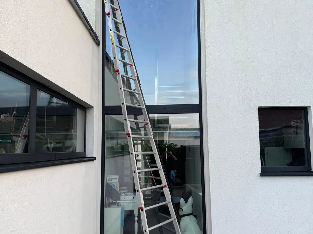 Haute fenêtre d'une maison avec grande échelle pour le nettoyage des vitres