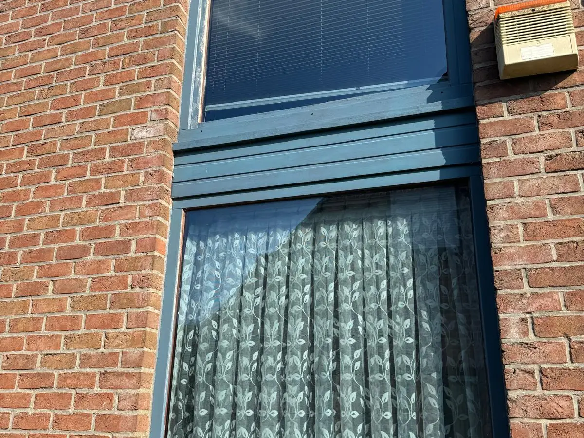 Fenêtre de façade en briques avec châssis bleu
