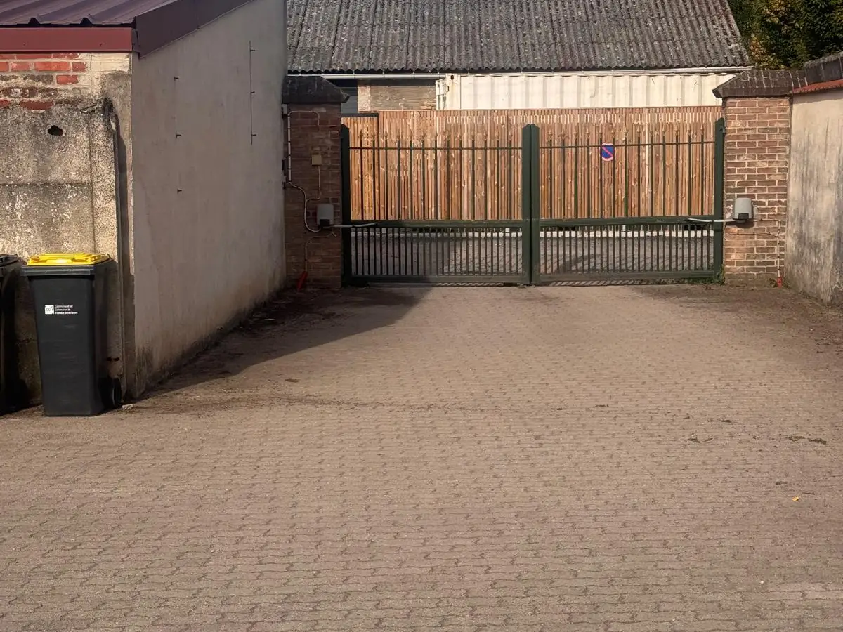 Cour pavée devant un portail en bois, pavés propres
