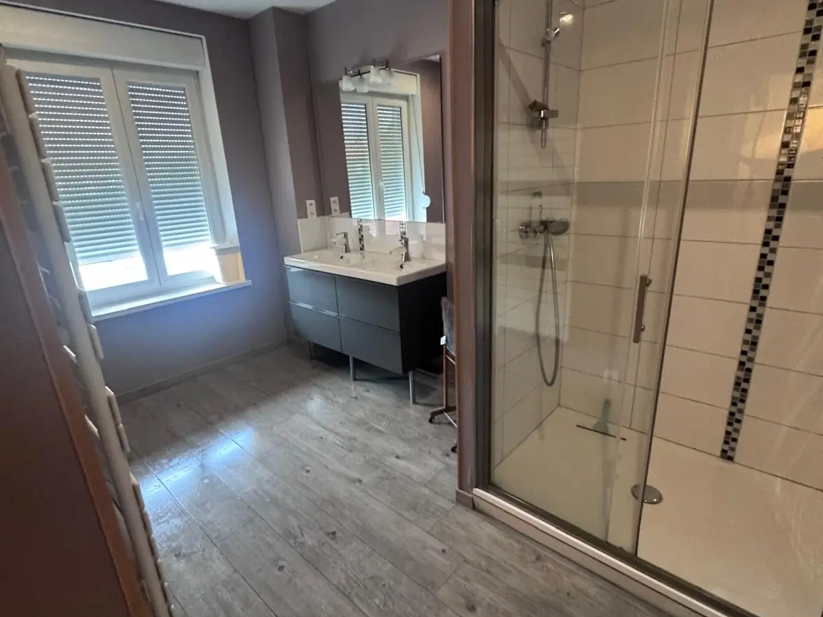 Salle de bain avec douche vitrée et double vasque, sol propre