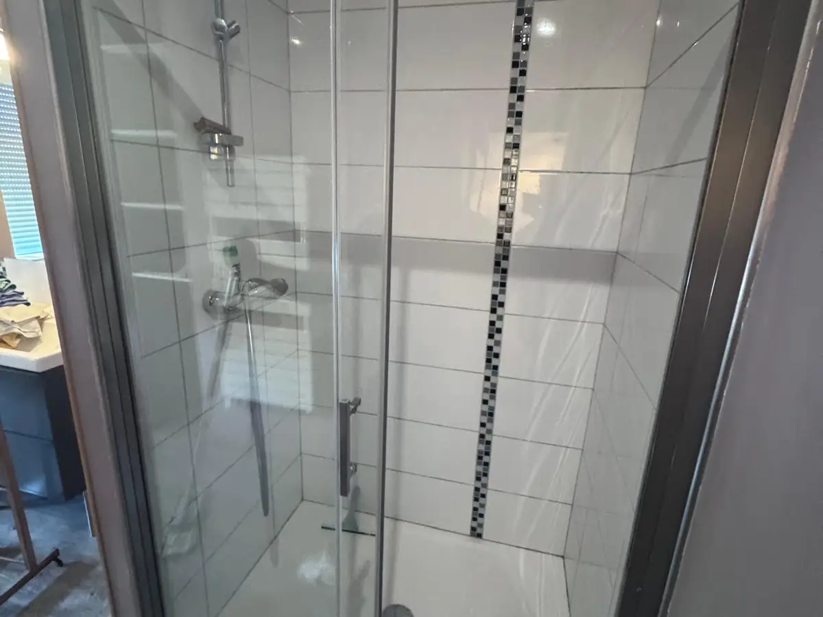 Cabine de douche à parois vitrées nettes et faïence blanche