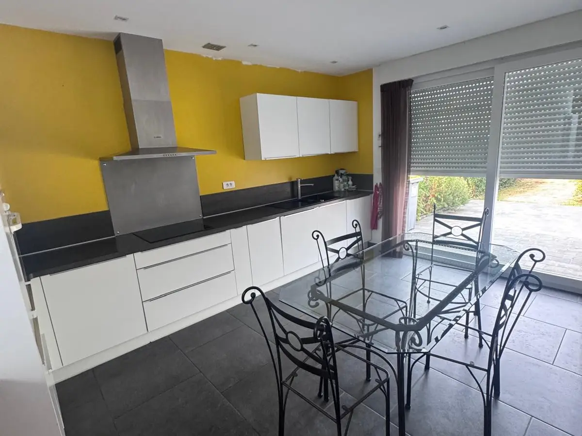 Cuisine aux murs jaunes avec table en verre, plan de travail propre