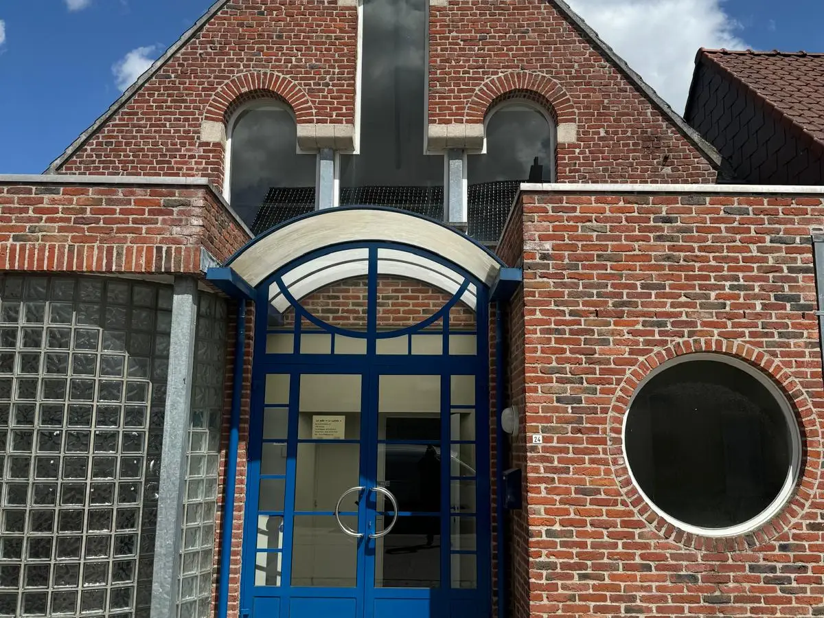 Porte vitrée à cadre bleu dans une façade en brique, vitrage net