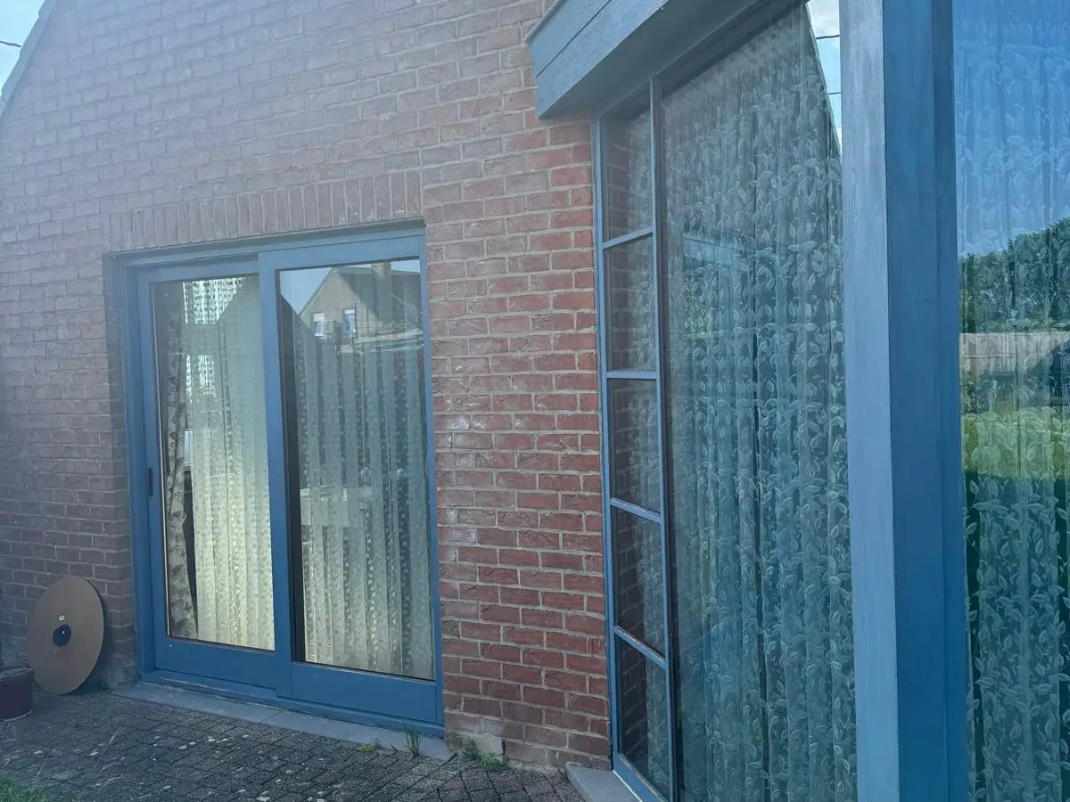 Baie vitrée à cadre bleu sur façade en brique