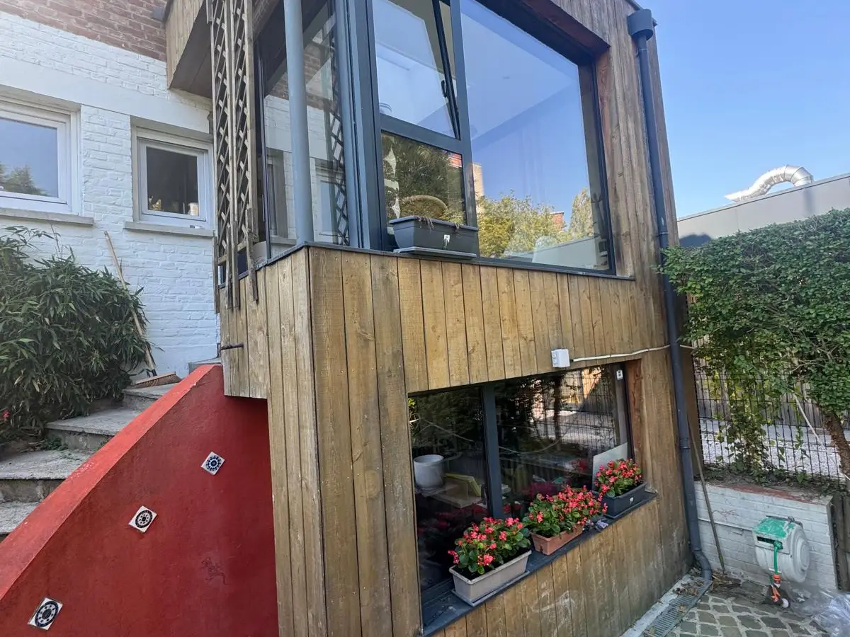 Façade en bois avec grande vitre et jardinière