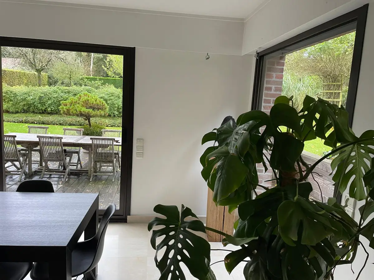 Salle à manger devant une grande baie vitrée sur jardin