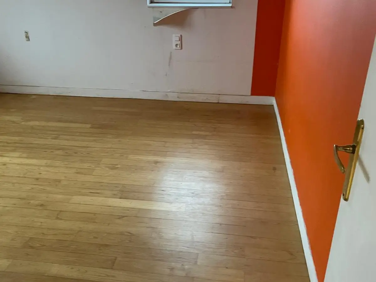Chambre vide au parquet propre, mur orange