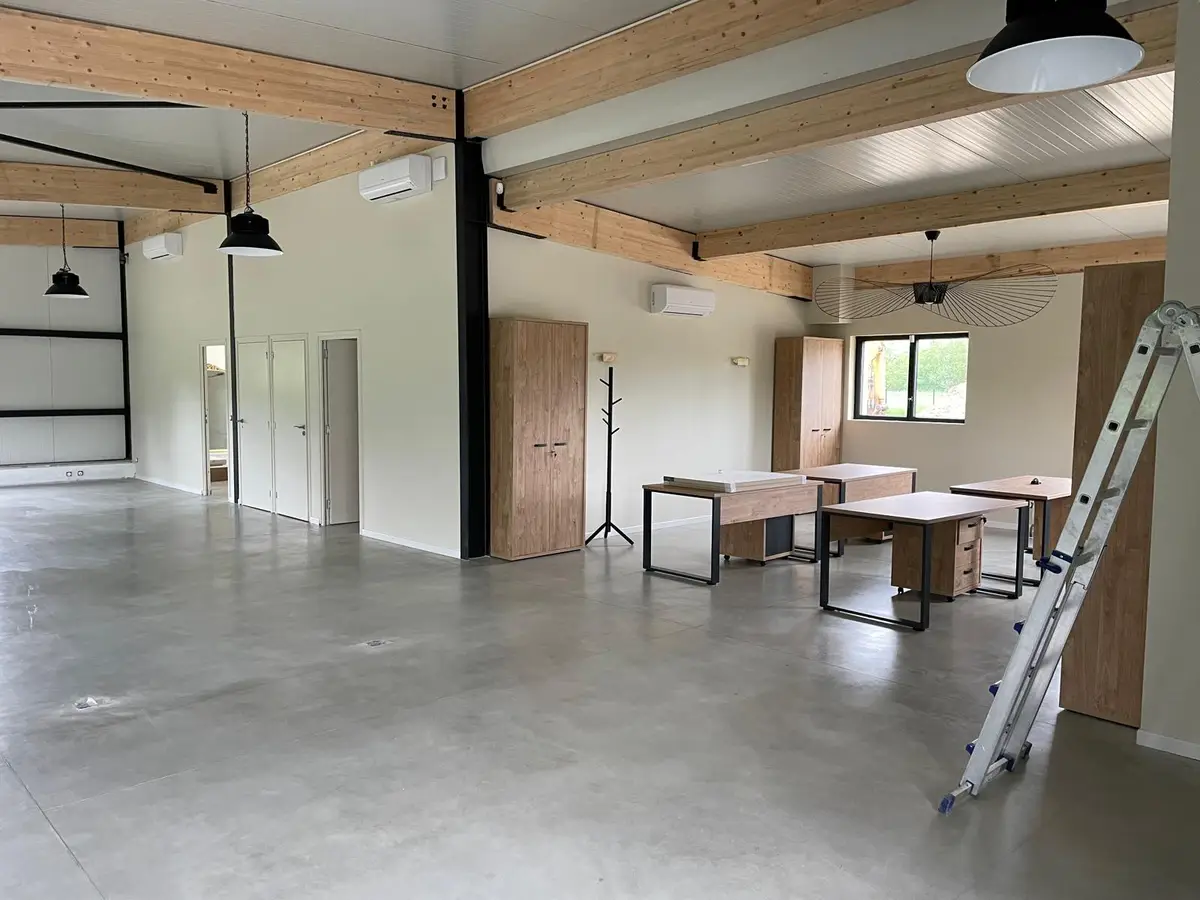 Grande salle a poutres bois et sol en beton cire nettoyes