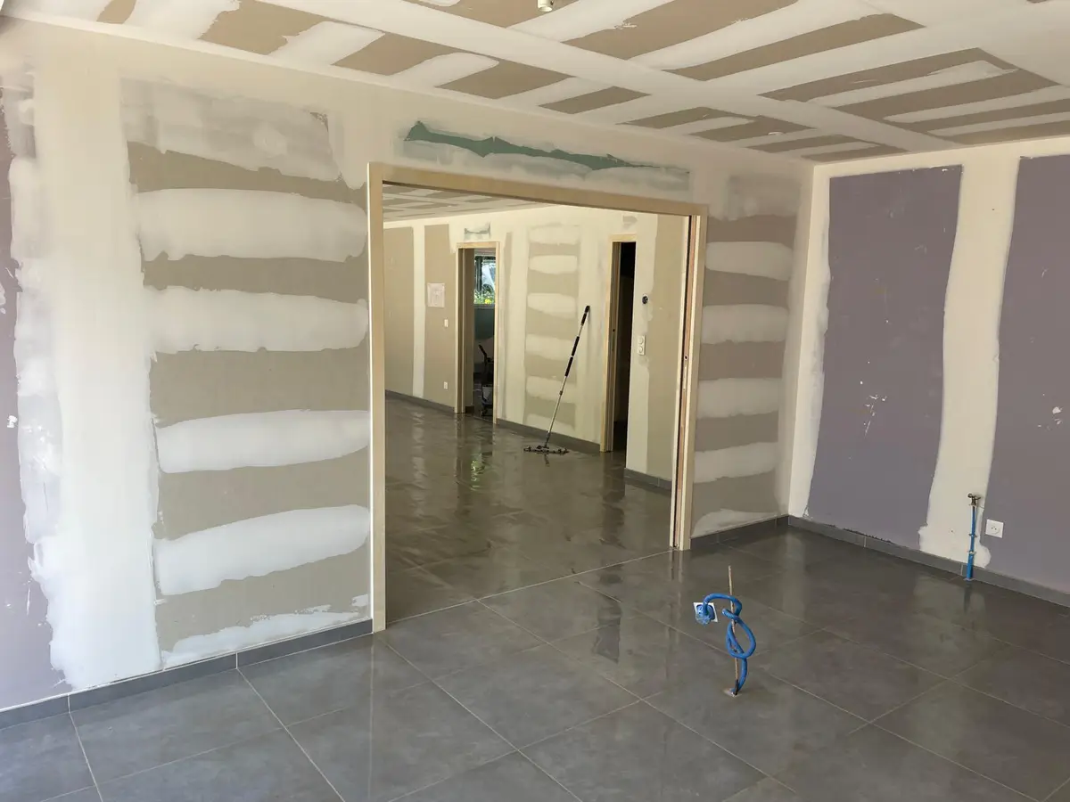 Grande piece au carrelage gris lave, cloisons en platre