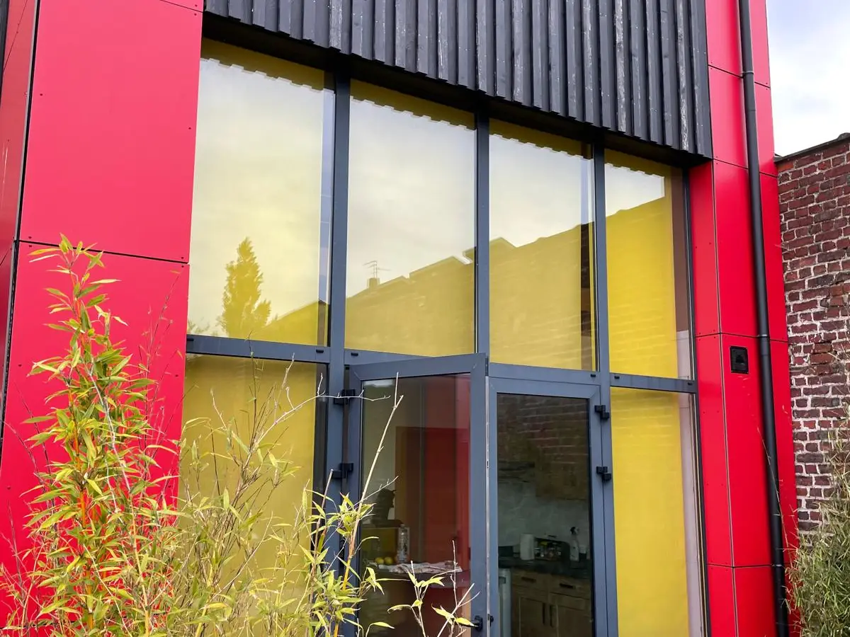Porte et vitrage en aluminium dans une façade rouge et noire