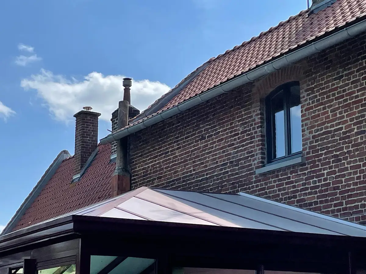 Véranda bordeaux et façade en briques, vitrage nettoyé