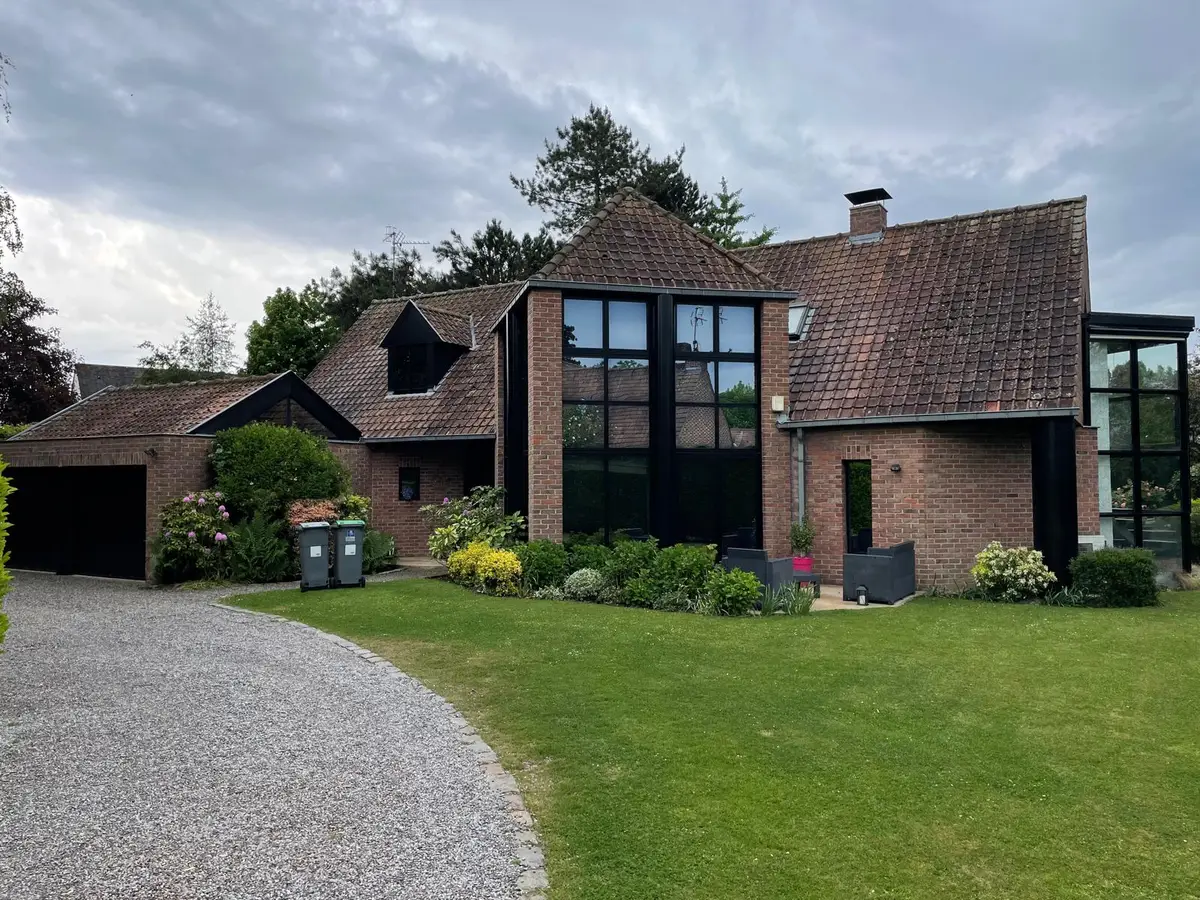 Maison en briques aux grandes baies vitrées noires, vitres propres