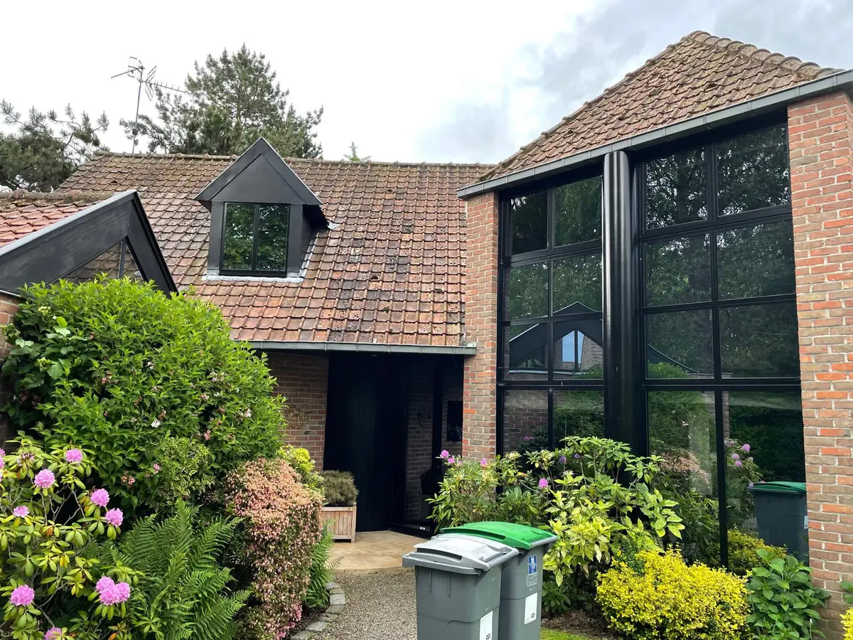 Maison en briques aux grandes baies vitrées noires, vitres propres