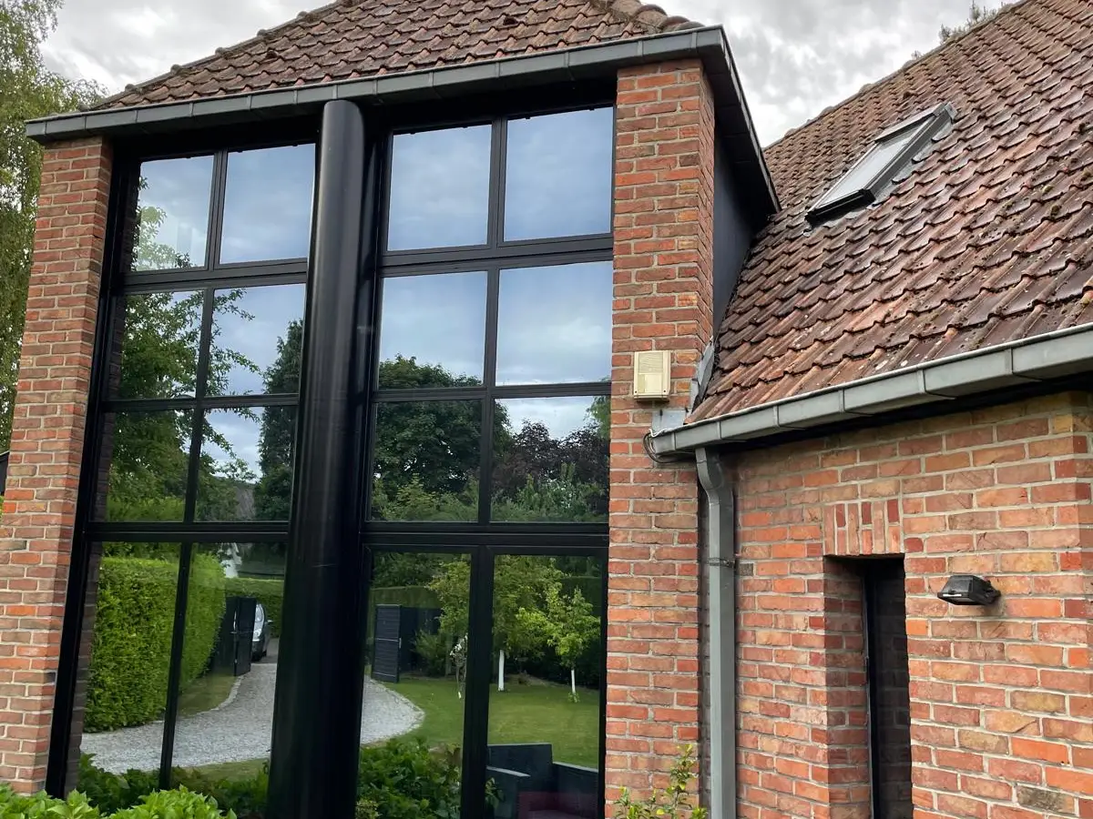 Maison en briques aux grandes baies vitrées noires, vitres propres
