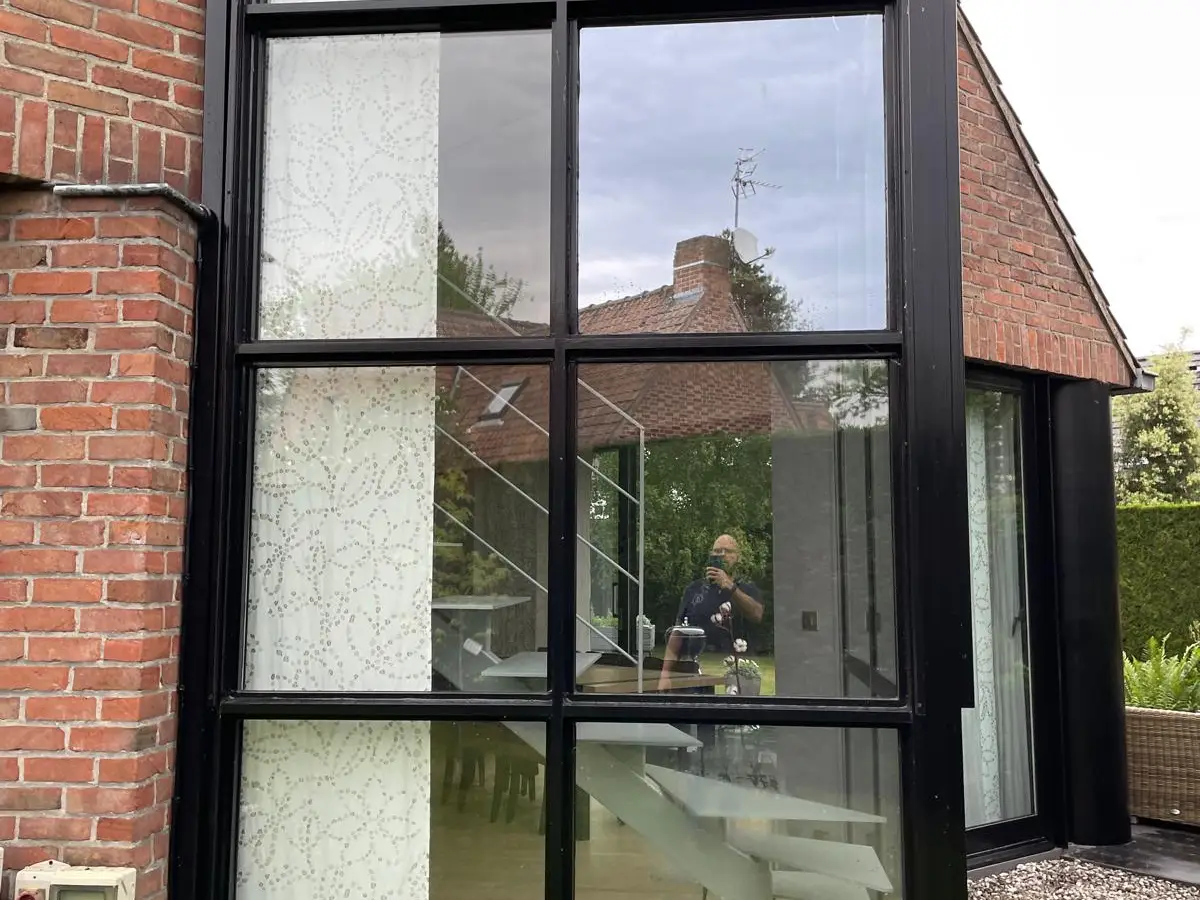 Maison en briques aux grandes baies vitrées noires, vitres propres