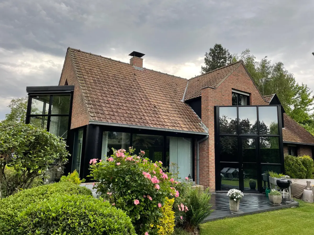 Maison en briques aux grandes baies vitrées noires, vitres propres