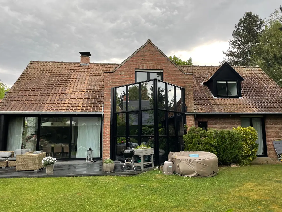 Maison en briques aux grandes baies vitrées noires, vitres propres