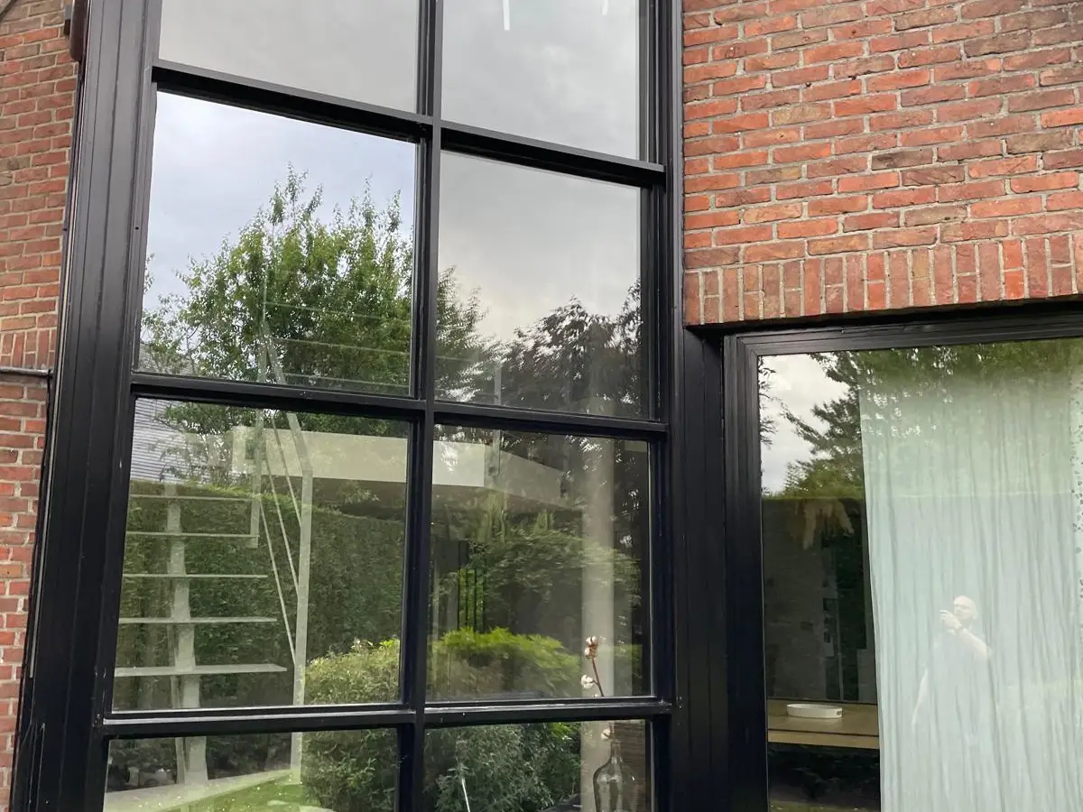 Maison en briques aux grandes baies vitrées noires, vitres propres