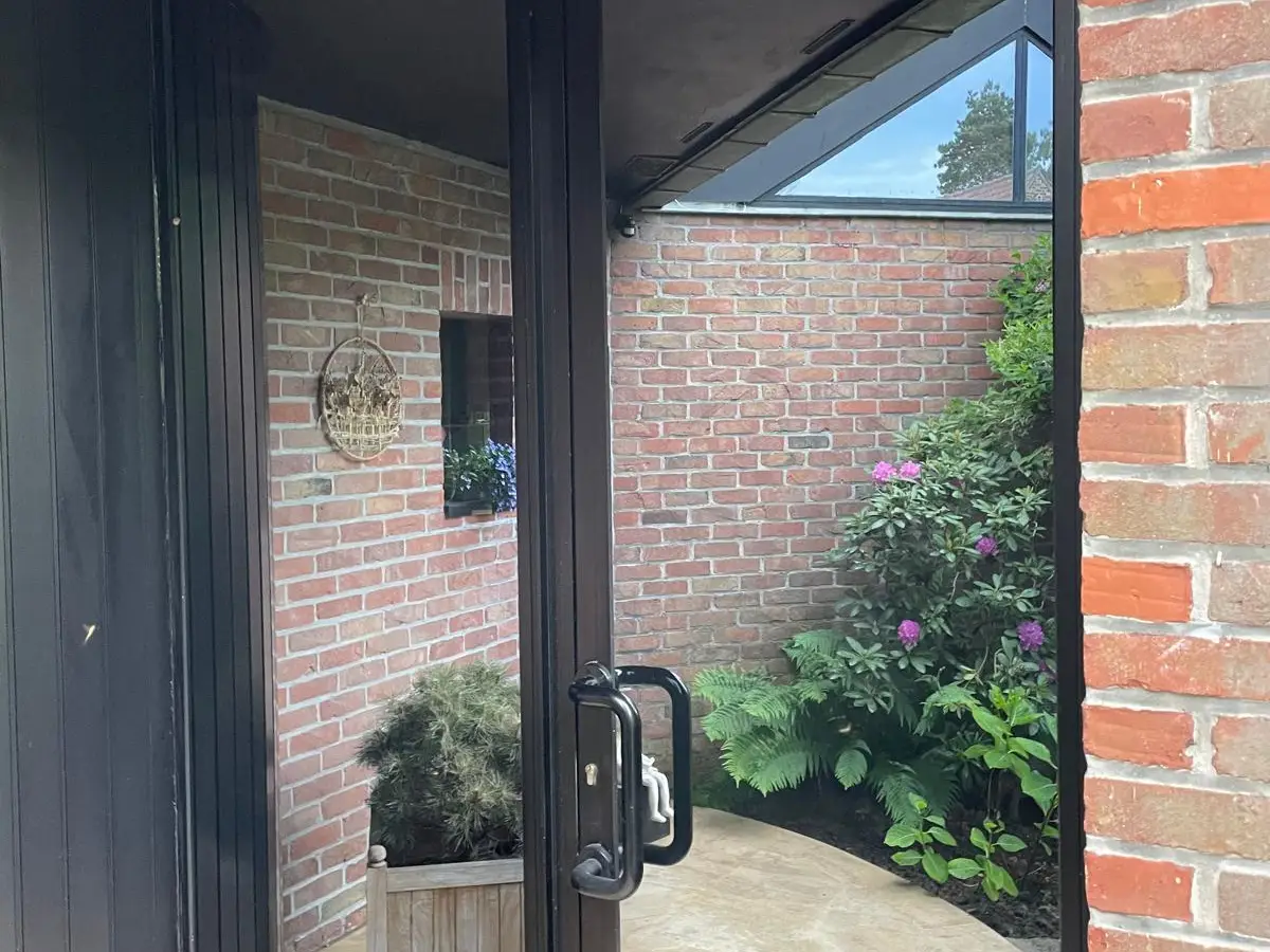 Porte vitrée noire donnant sur une cour intérieure