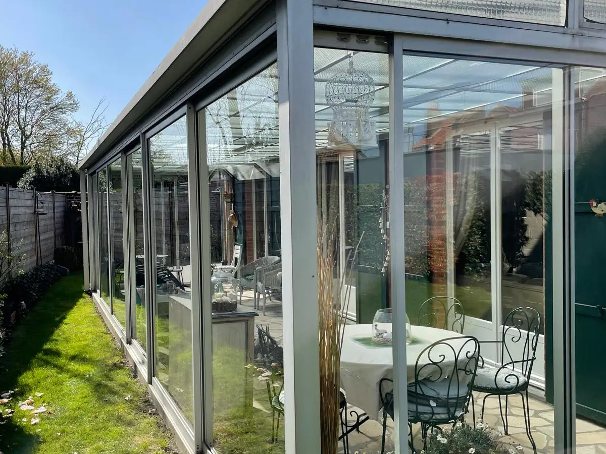 Véranda en aluminium aux vitres propres, table de jardin
