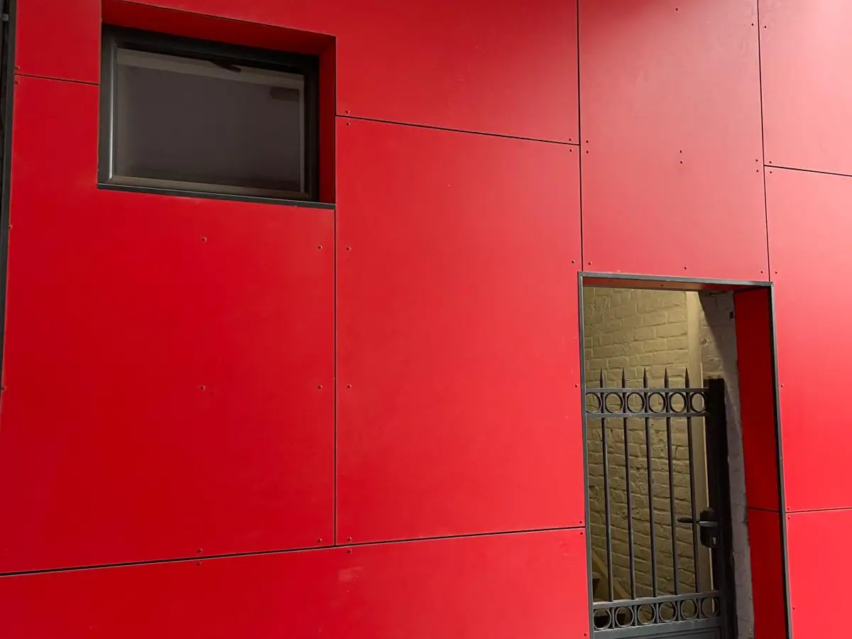 Façade rouge et noire d'un bâtiment, accès commun